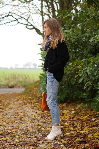 Черный бархатный свитер с круглым вырезом и голубые рваные джинсы-бойфренды — стильный выбор девушек, которые постоянно в движении. Что касается обуви, можно отдать предпочтение комфорту и выбрать белые ботинки.