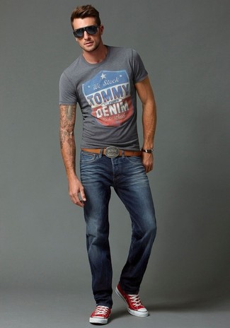 Серая футболка с круглым вырезом с принтом и темно-синие джинсы — отличный вариант для вечера в компании друзей. Чтобы образ не получился слишком отполированным, можно завершить его красными кедами.